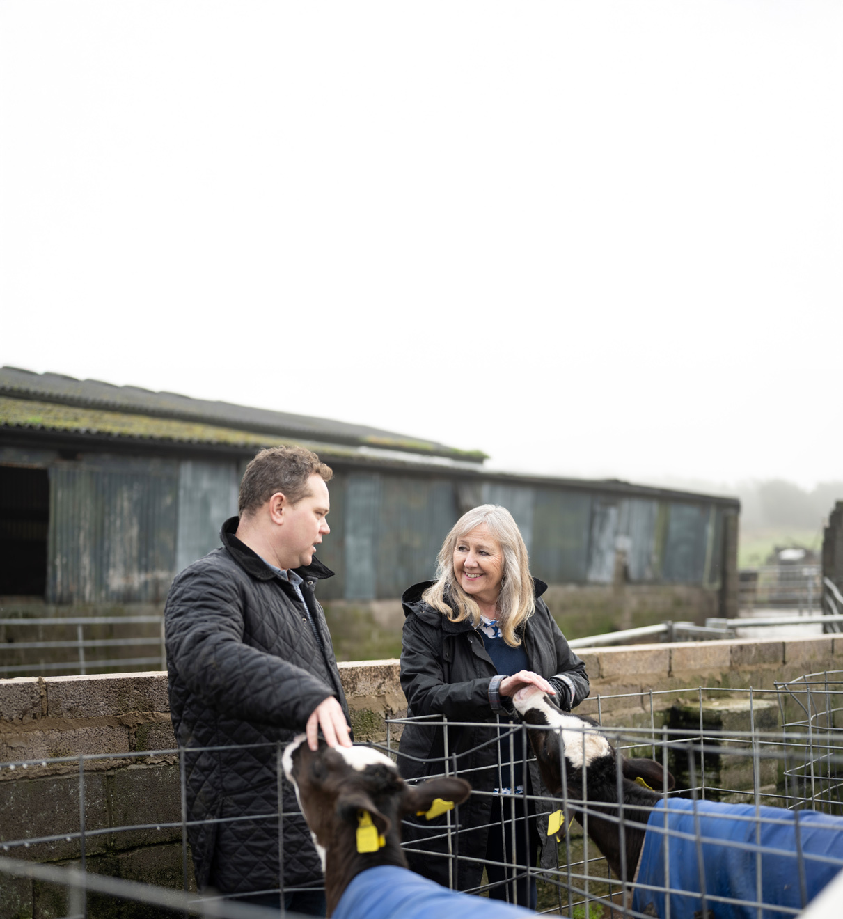 Man and women chatting with a farm building in the background