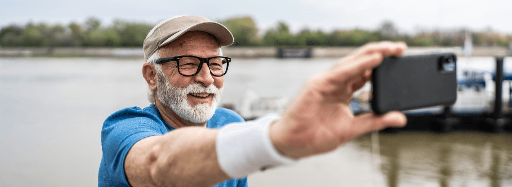 senior man taking a selfie at a lake