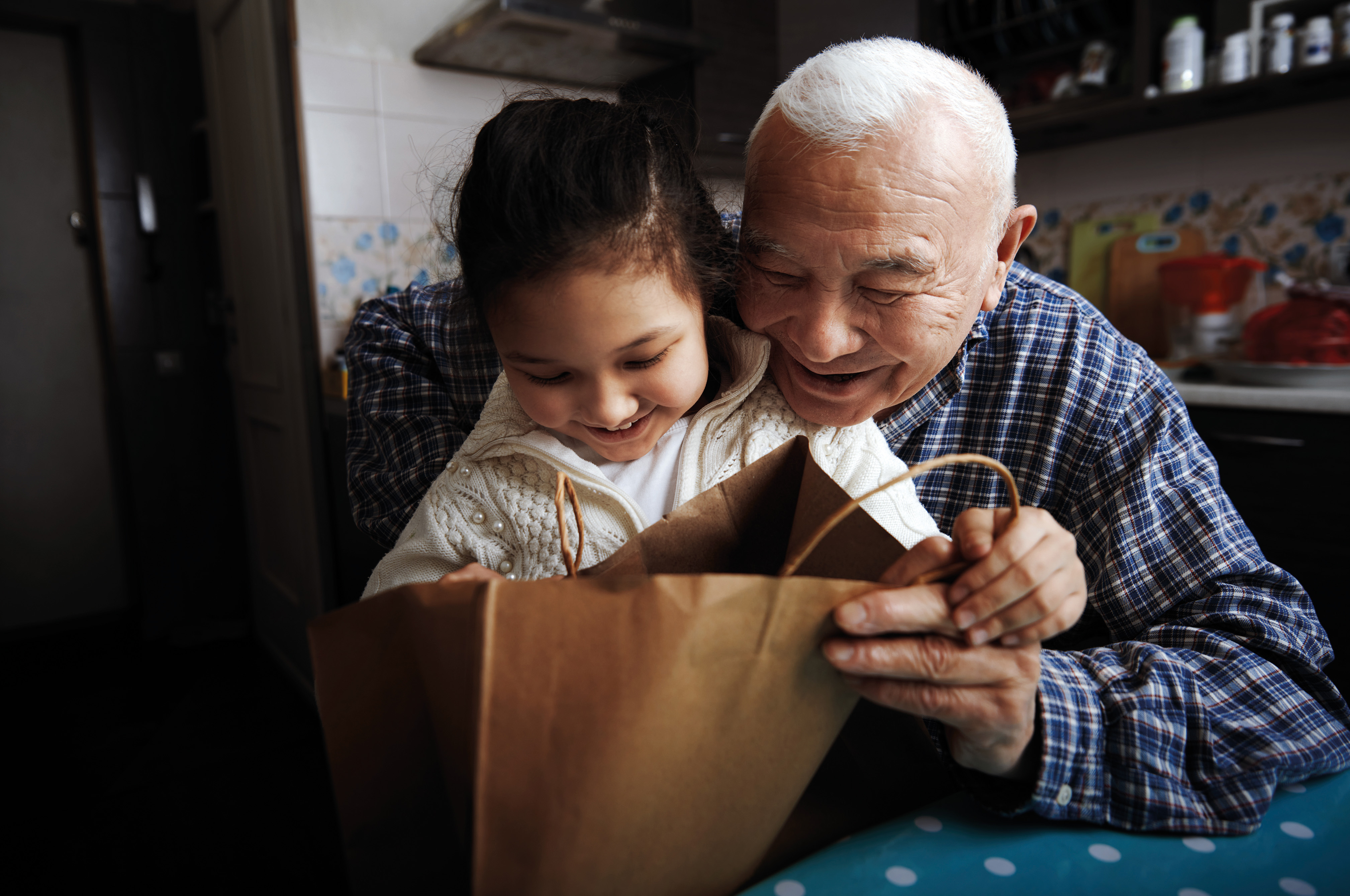 Grandfather and granddaughter looking in a paper shopping bag