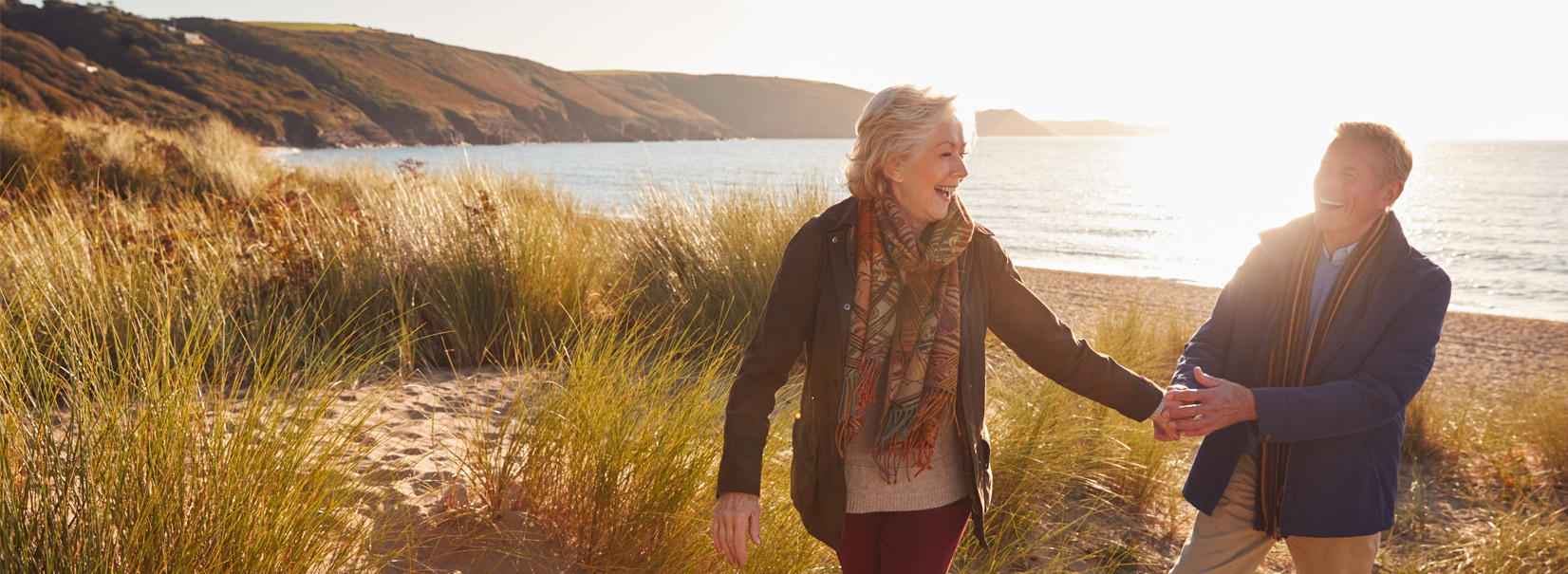 Older couple walking along the beach smiling