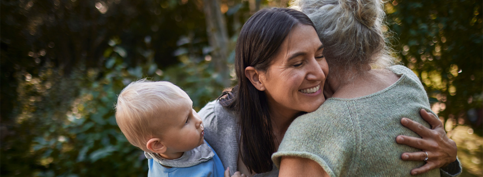 mother hugging mother whilst holding her son