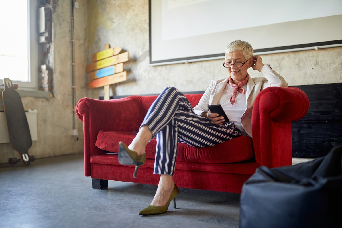 An elderly female boss is using a smartphone while taking a break