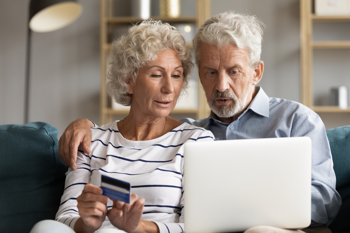 Senior couple use online websites with bank credit card